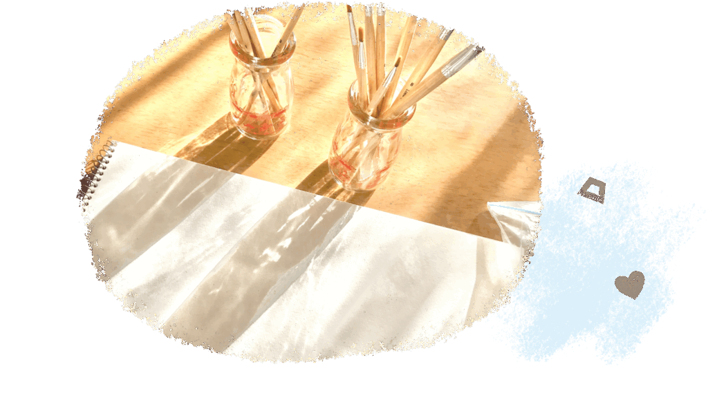 明るい室内のイメージ写真。画用紙と筆が写っている。